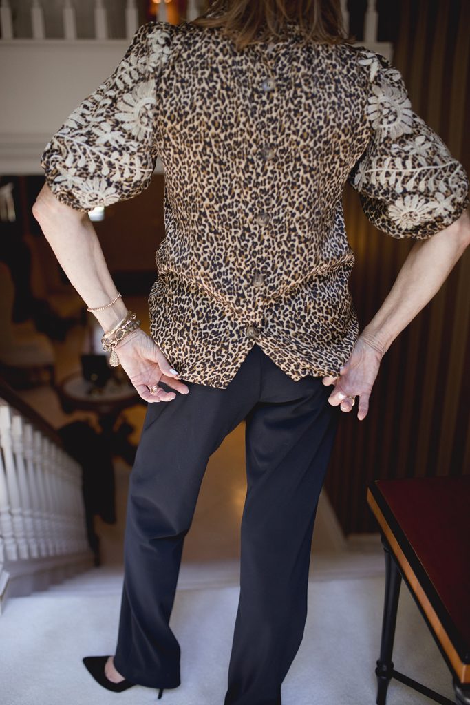 Leopard print short sleeved blouse shown with black pants and off white pants