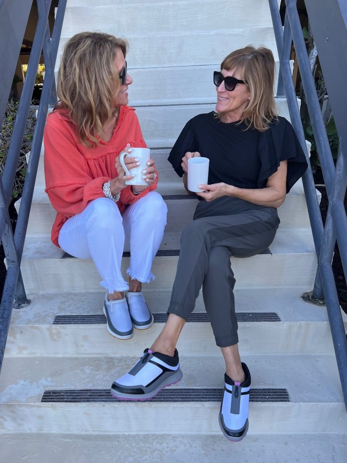 two women sitting on stairs talking